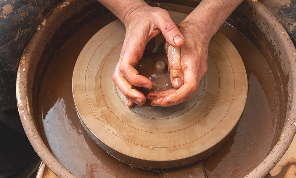 Mark works some clay on a wheel at Potters Thumb