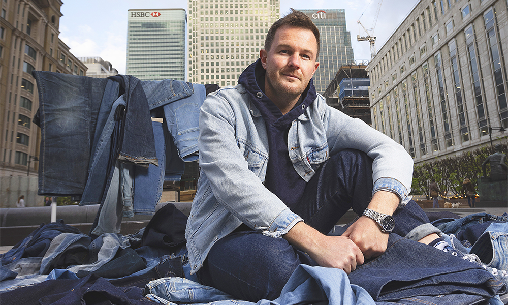 Artist Ian Berry, pictured surrounded by jeans in Cabot Square