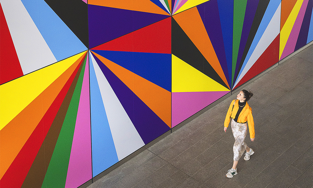 A Wharfer walks past Electro-Rainbow at Crossrail Place