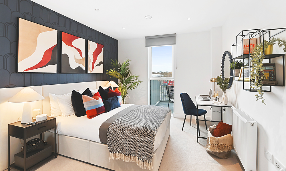Image shows a show home bedroom at Kidbrooke Square with a bed, desk, chair and brightly coloured art on the walls