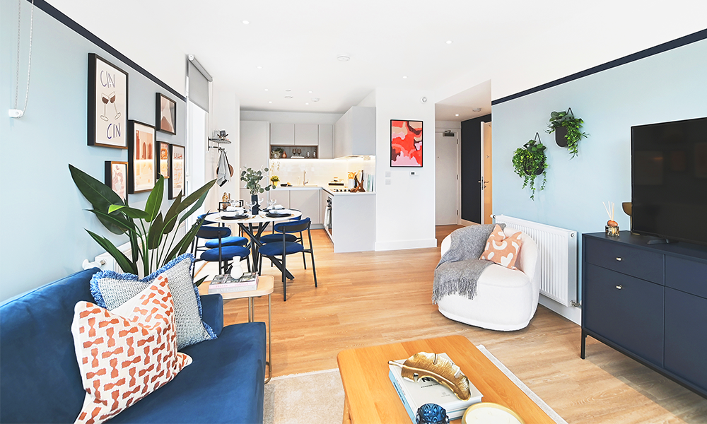 Image shows a show home at Kidbrooke Square with wooden floors and comfortable furnishings. The room is an open-plan living area with a kitchen