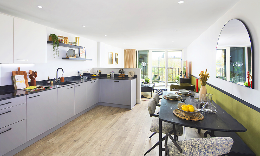 A show home interior at Square Roots Lewhisham showing a grey kitchen and an open-plan living area