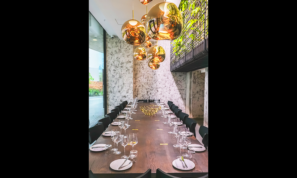 An image of a large dining table at the restaurant in Canary Wharf with place settings. Large golden light fittings hang above