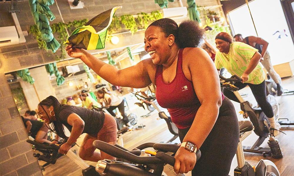 A group of people participate in a spin class on exercise bikes at The Body People