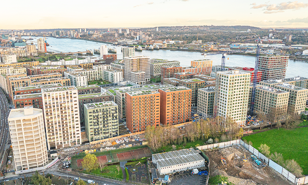 Image shows a collection of residential tower blocks that make up the Riverscape development next to the Thames in Royal Docks. East River Wharf's buildings are orange and at the centre