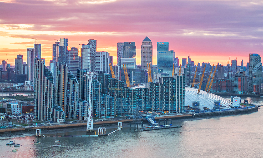Image shows the Greenwich Peninsula and Canary Wharf skylines at sunset as seen from Riverscape's residents' lounge