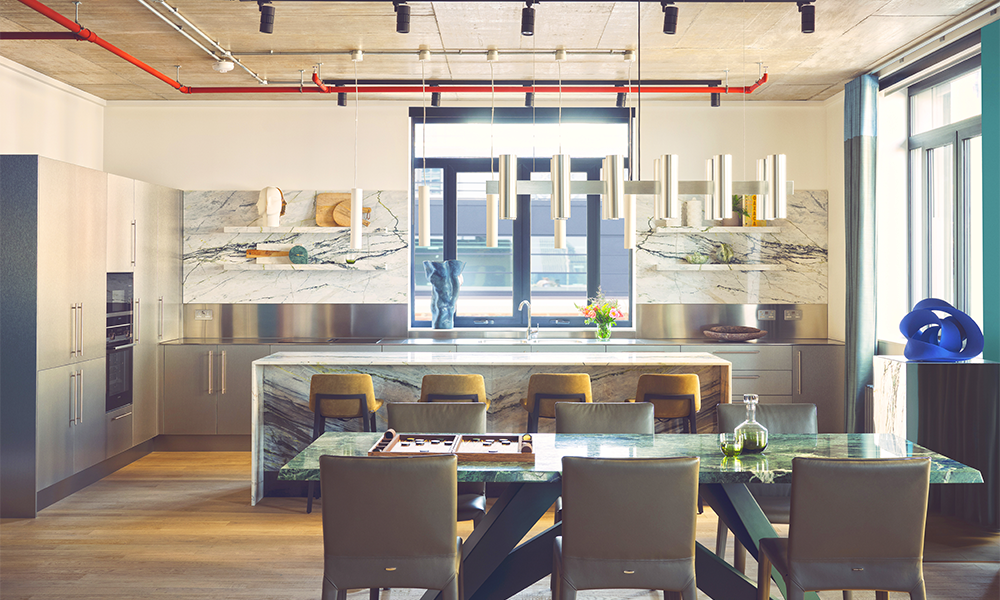 Image shows a stainless steel kitchen in one of The Upper Lofts at 8 Harbord Sqaure with a marble table and breakfast bar in the foreground