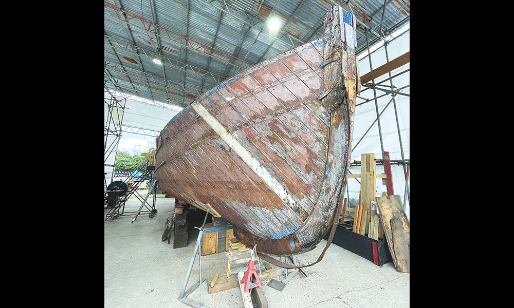 Image shows the Frederick Kitchen, a stripped down wooden boat sat on supports, as work continues