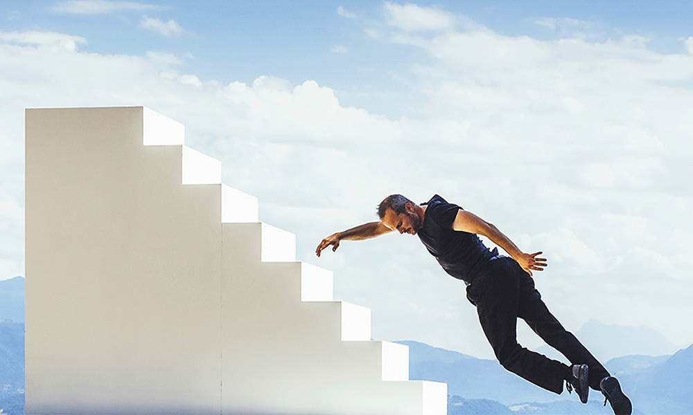 Image shows a dancer dressed in black interacting with a staircase ahead of Greenwich + Docklands International Festival in Septemeber 