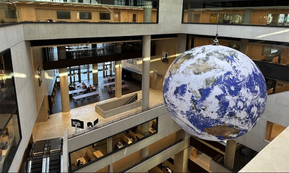 Image shows a sculpture of the Earth hanging inside a large concrete atrium at UCL East on the Queen Elizabeth Olympic Park