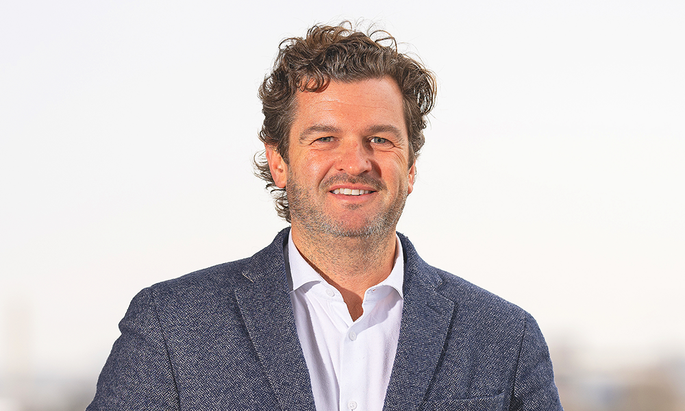 Image shows Excel's director if immersive entertainment and events, Damian Norman – a man with curly brown hair in a jacket and white shirt