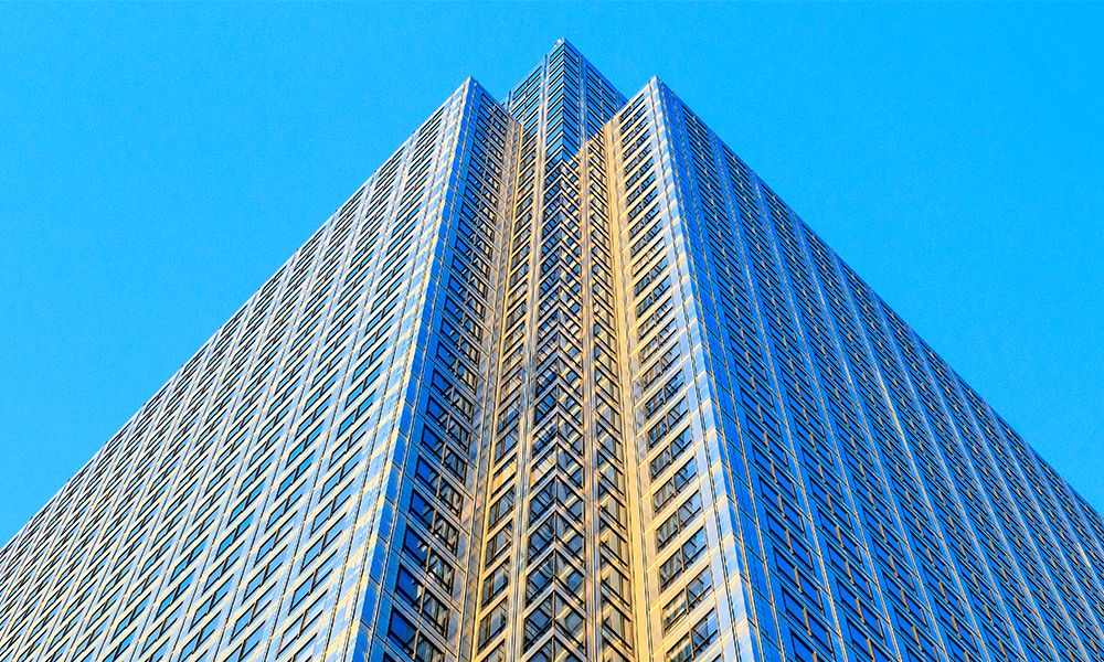 Image shows an image of One Canada Square in Canary Wharf, a stainless steel-clad office block below a blue sky.