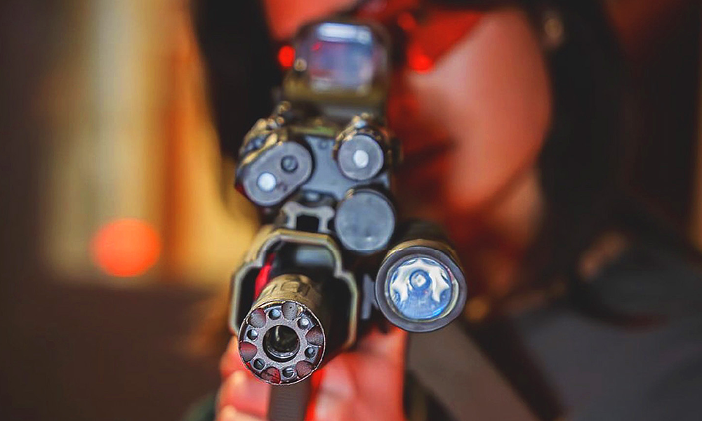 A woman points an Airsoft gun at the camera