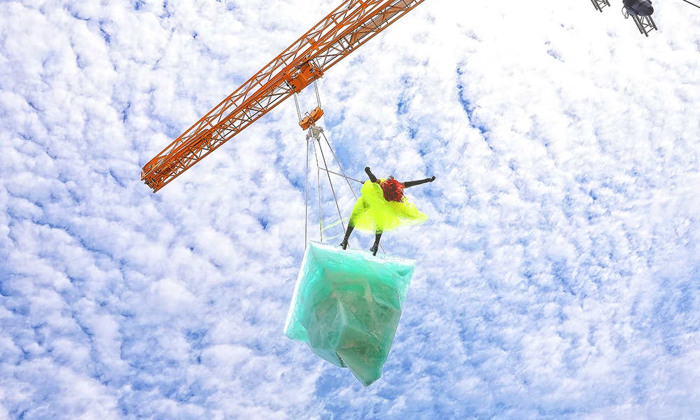 Image shows a performer on the edge of a 2/5 tonne block of ice suspended from a crane