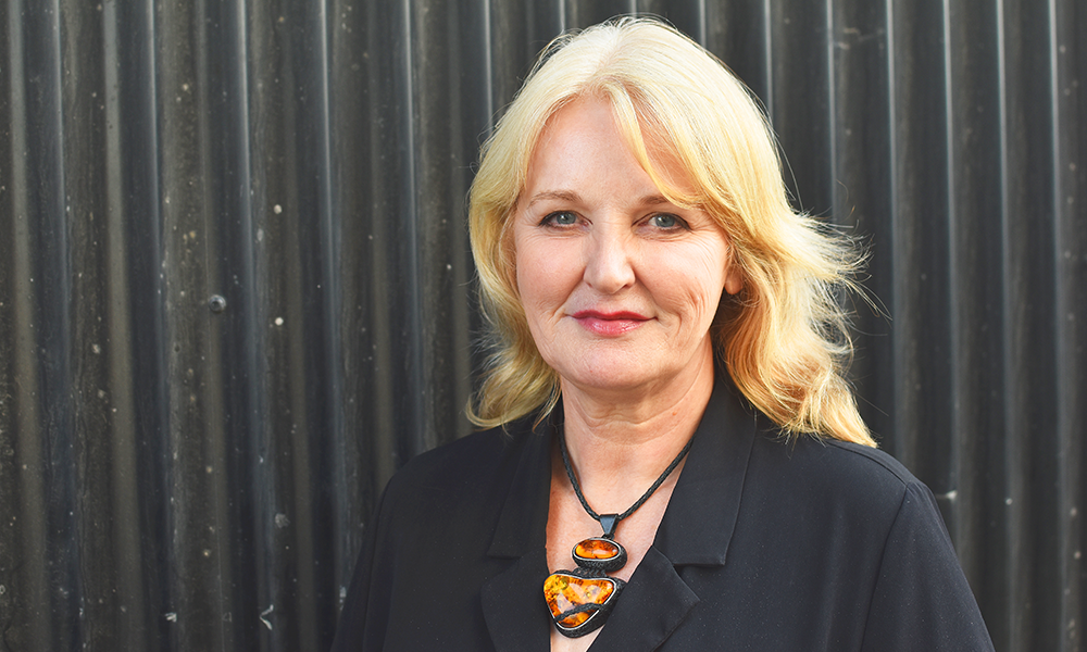 Image shows Alison Lowe of UEL, a blonde woman wearing a black dress with an amber necklace