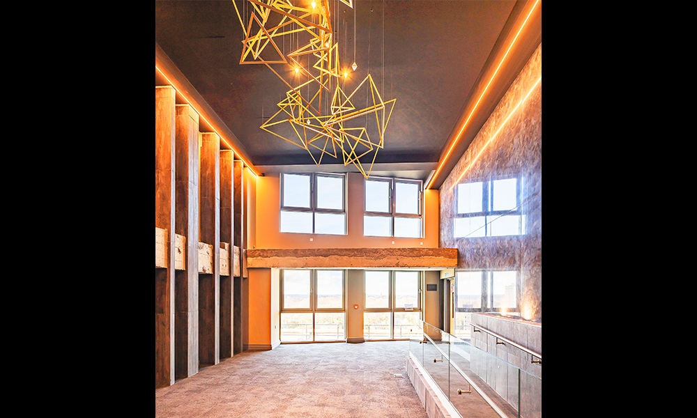 Image shows the private penthouse foyer at Warley HQ with a gold metal light fitting and double height glazing