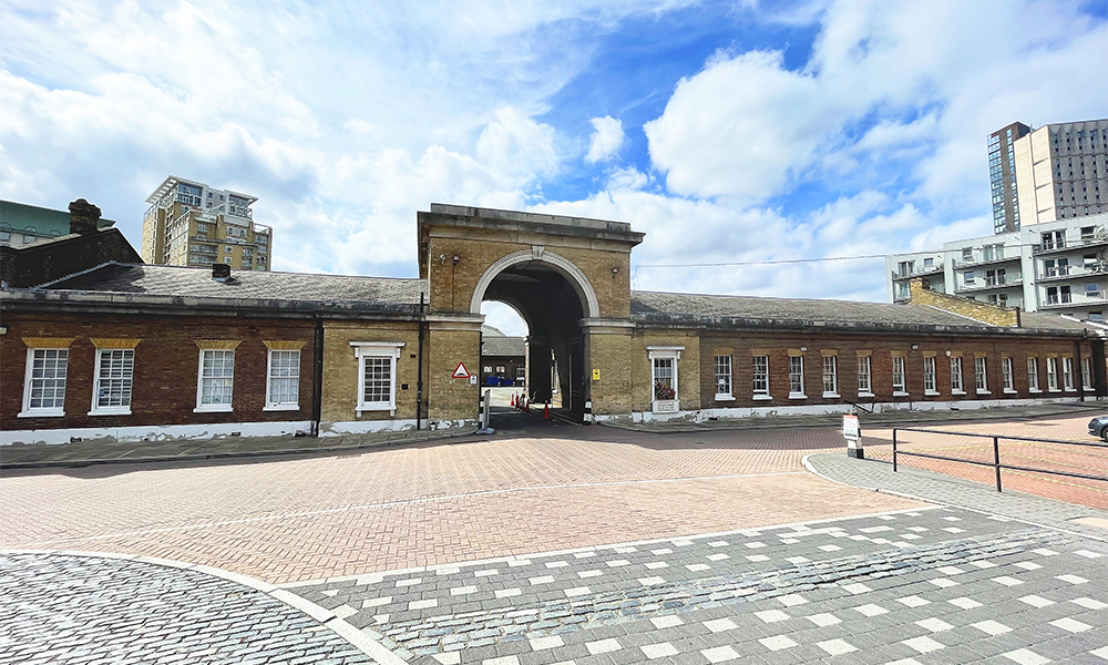 Image shows the brick buildings of Cannon Workshops under a blue sky with white clouds