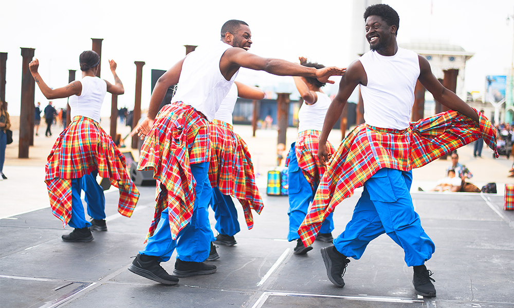 Image shows dancers in tartan kilts, white shirts and blue trousers