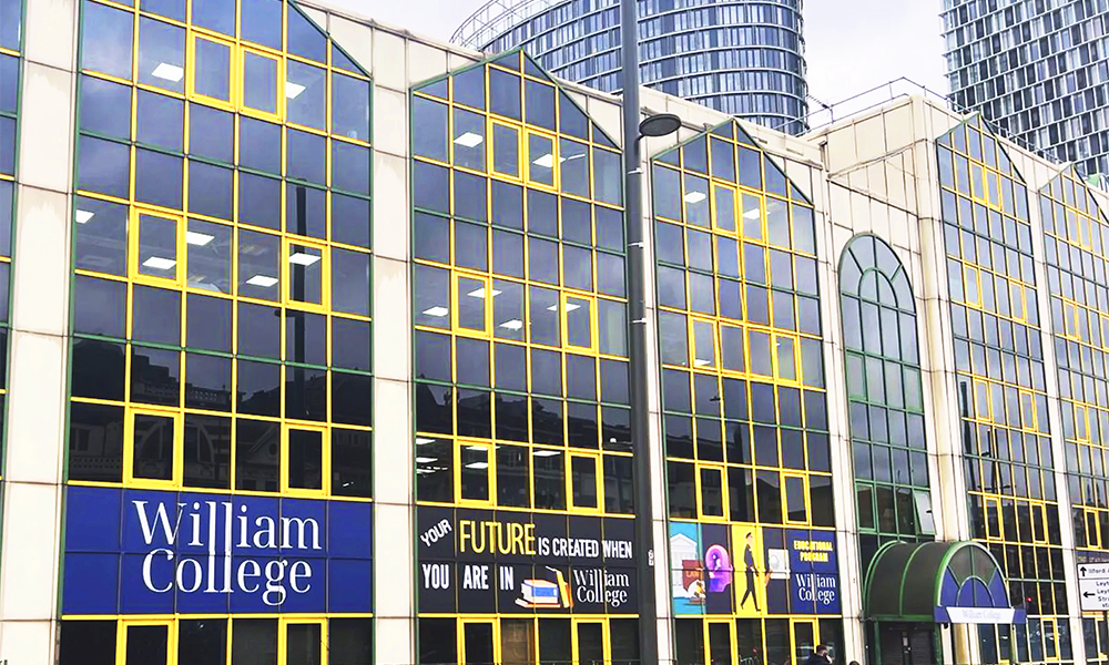 Image shows the exterior of William College in Stratford, an office block with yellow window frames