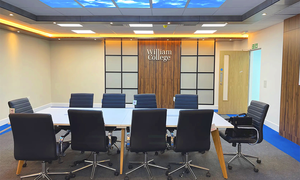 Image shows a meeting room at William College with leather chairs and a blue and white colud design on the ceiling