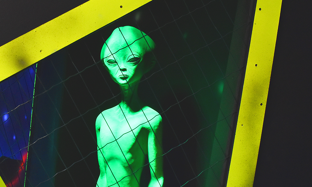 Image shows a green alien in a cage at the venue