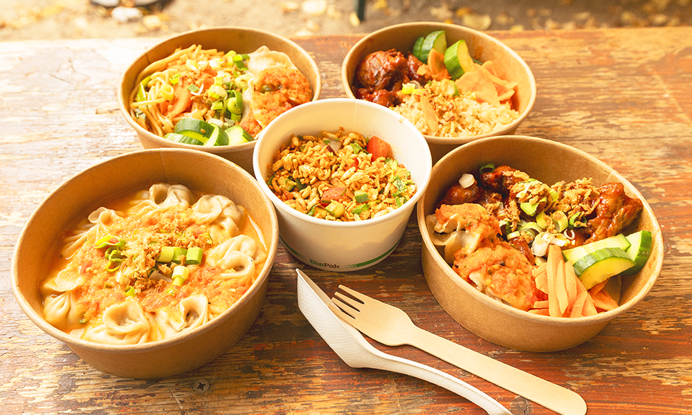 Image shows a selection of street food from Hamro Maya on a wooden table in cardboard bowls