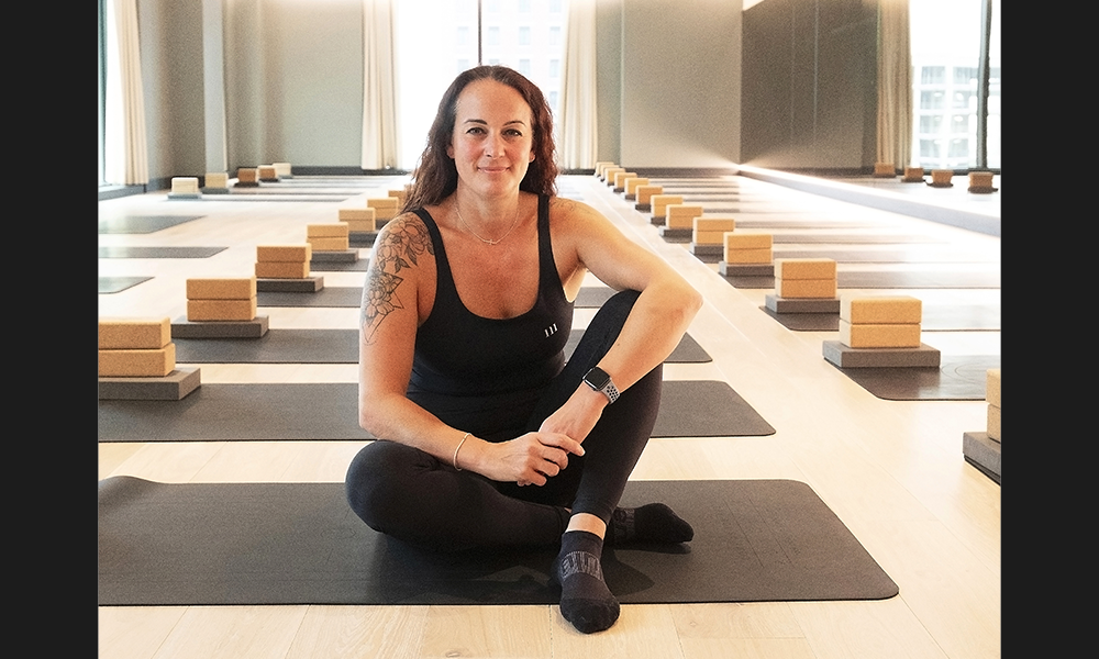 Third Space Canary Wharf group exercise manager Vicki Antoniou, a woman sat in a hot yoga studio smiling at the camera