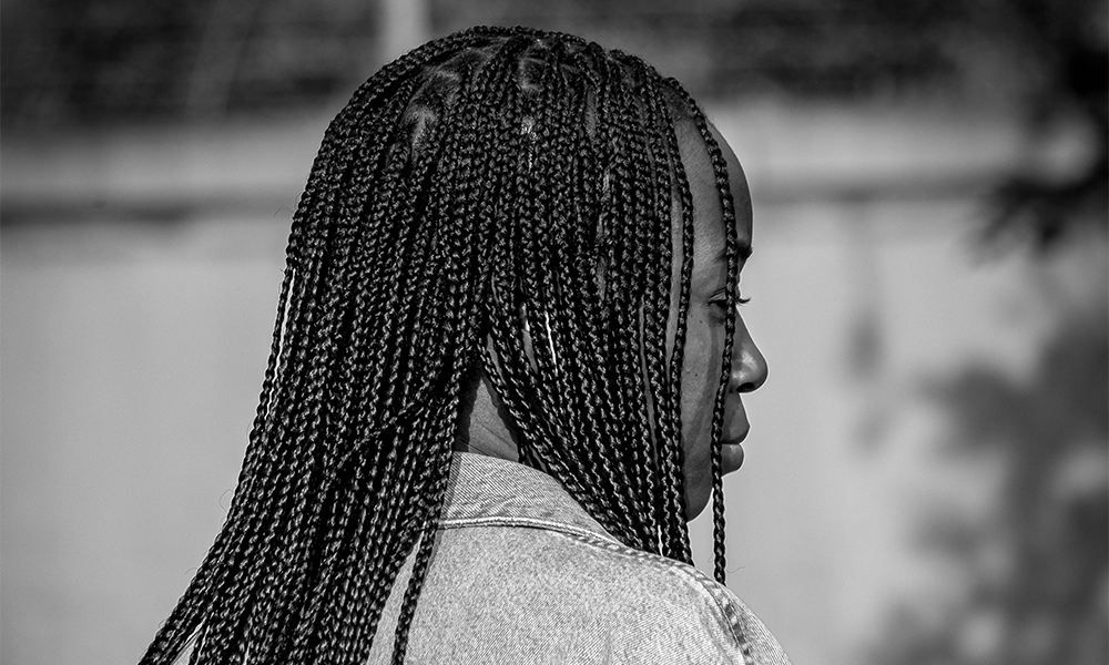 Image shows a woman with braided hair in a denim jacket