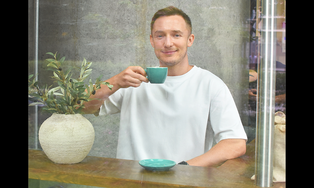 Image shows Daniel Bull, the man behind The Eleventh Hour and The Lockdown Room, drinking a cup of coffee