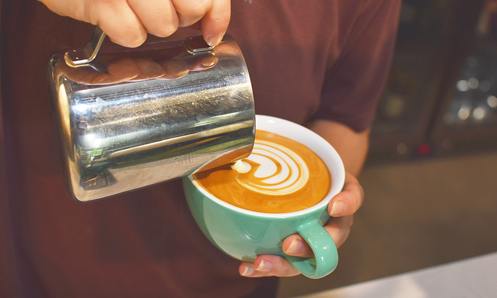 A staff member makes a coffee at The Eleventh Hour