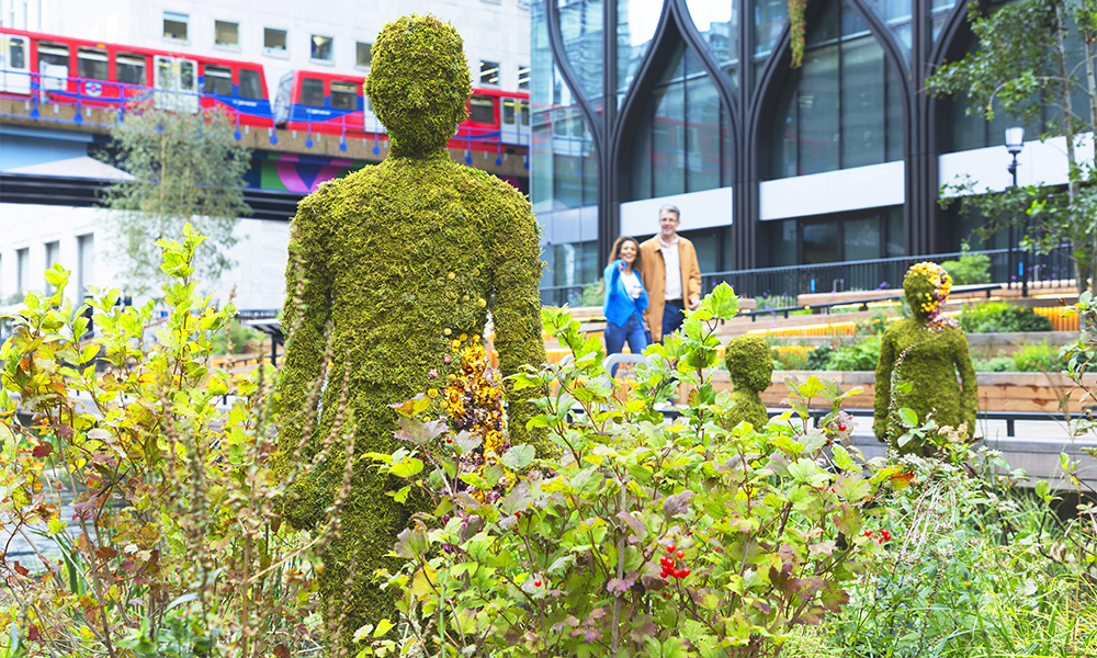 Image shows a couple looking at a series of living, mossy figures at Eden Dock